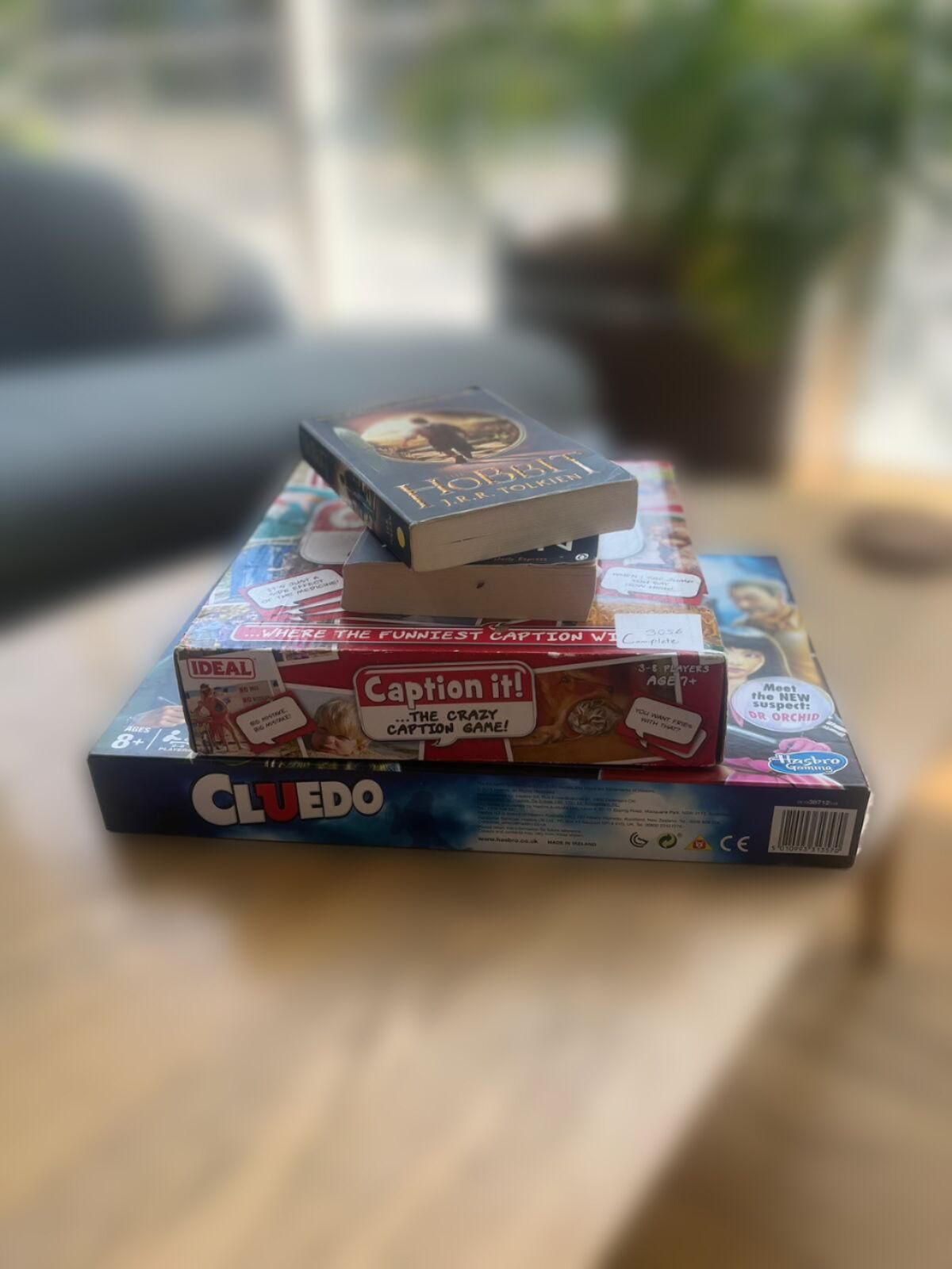 A stack of books on a table with a window in the background.