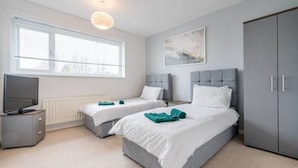 A bedroom with two beds, a wardrobe, a television, and a window. - Bright & Airy 3BR Home with Parking (Sheffield)