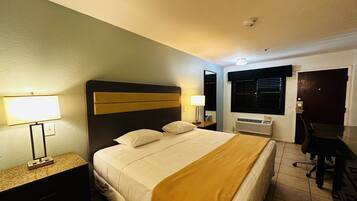A hotel room with a bed, bedside lamps, a desk, and a chair.