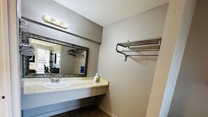 A bathroom with a sink, mirror, towel rack, and a trash can. - Casa Blanca Express & Suites Cypress Buena Park - Anaheim Area (Cypress)