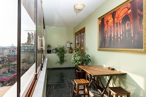 Enjoy the city view from this balcony with a table, chairs, and a potted plant.