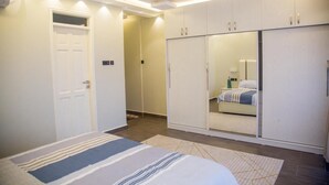 A bedroom with a bed, a wardrobe, and a mirror. - LUXE-3BEDROOM CONDO WITH LAKE AND GOLF COURSE VIEWS (Kampala)