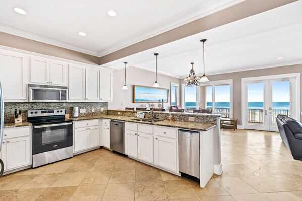 A spacious kitchen with white cabinets, stainless steel appliances, and a large island.