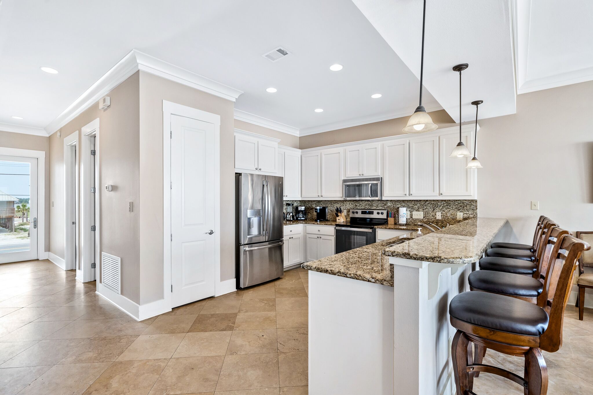 A modern kitchen with white cabinets, stainless steel appliances, and a granite countertop.