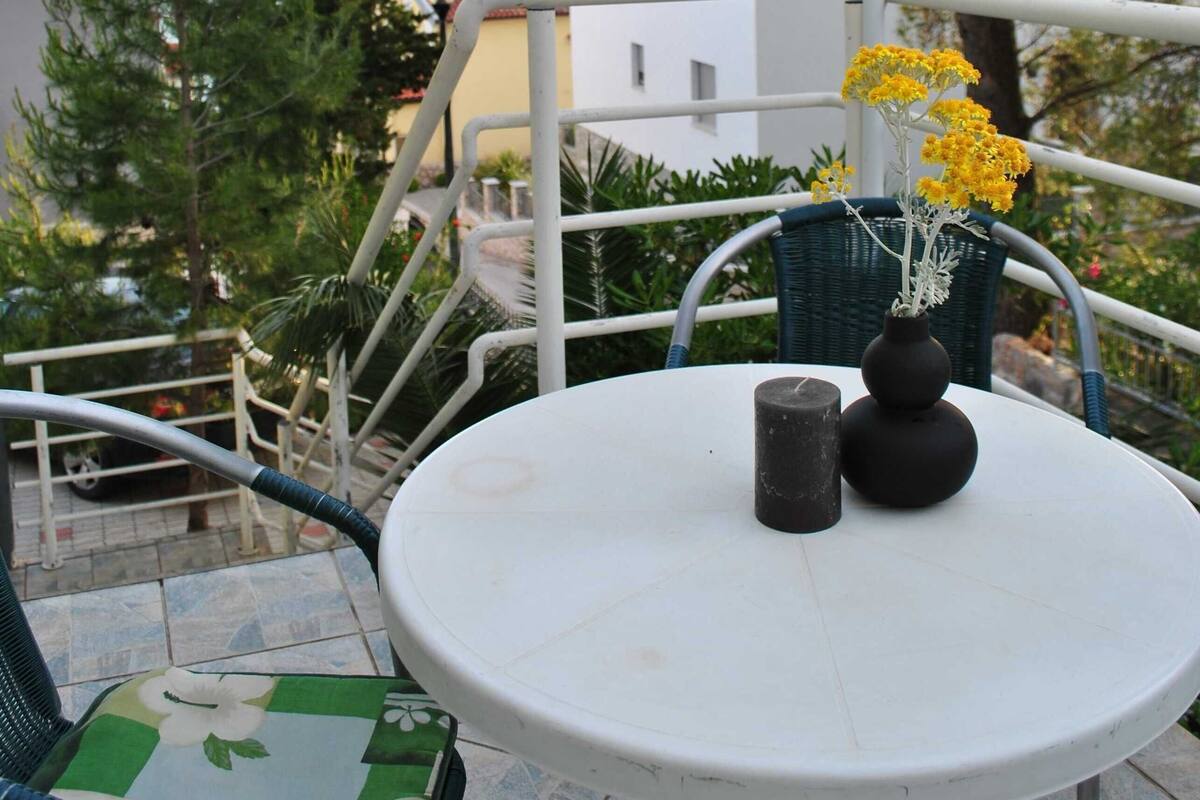 A round table with a vase of yellow flowers and two candles on a terrace with outdoor seating.