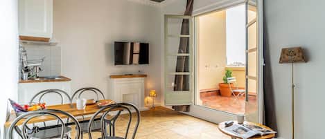 A compact living space with a dining area, kitchenette, and a view through an open door.