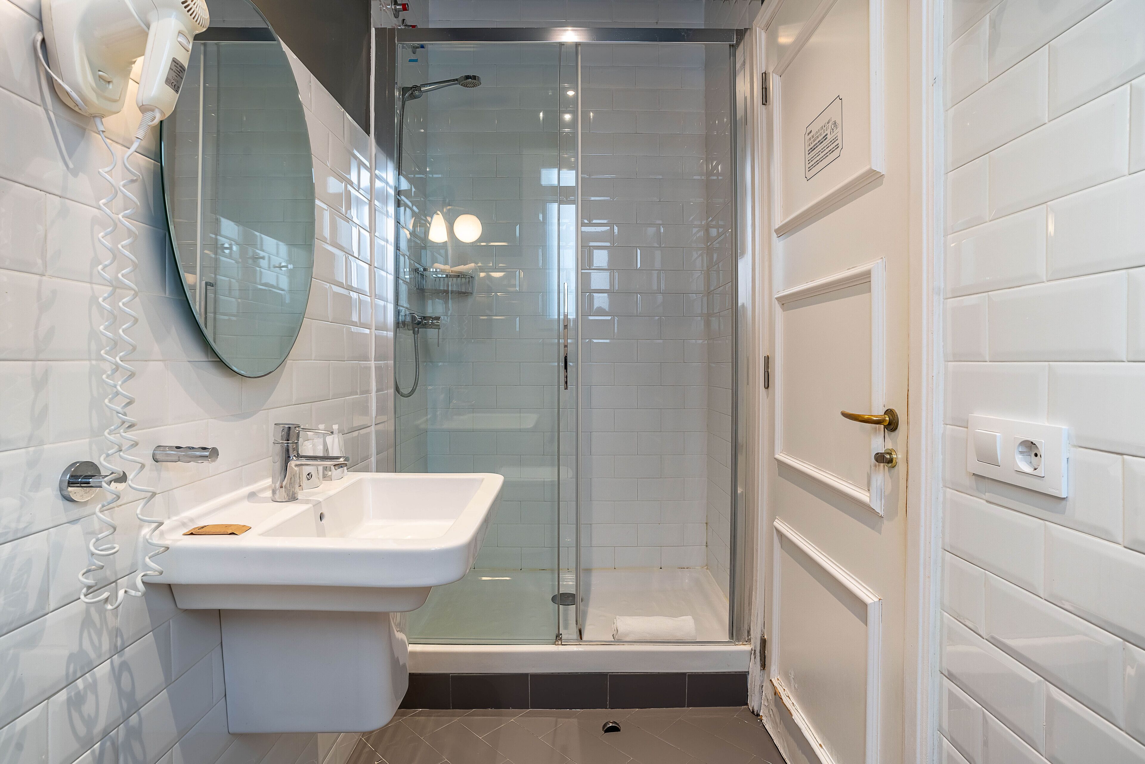A modern bathroom with a glass-enclosed shower, a white sink, and a mirror.