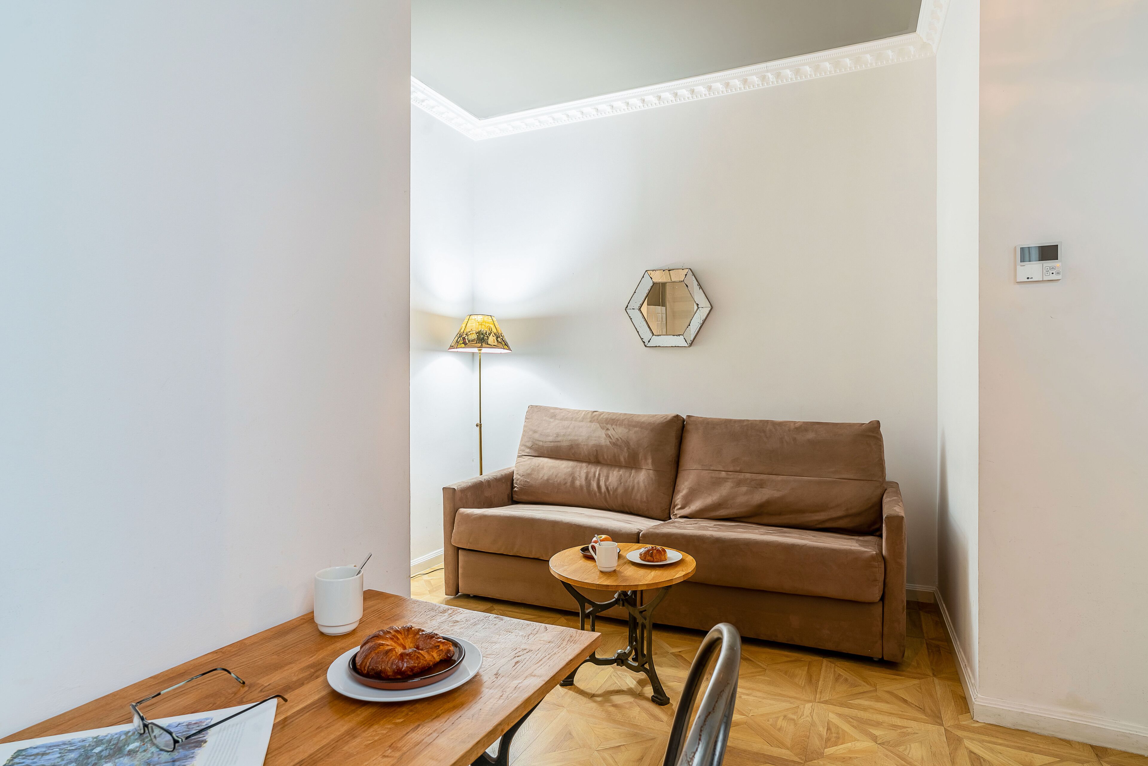 Un salon chaleureux avec un canapé marron, une table basse en bois et une lampe.