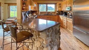 A spacious kitchen with a large island, wooden cabinets, and a stainless steel refrigerator.