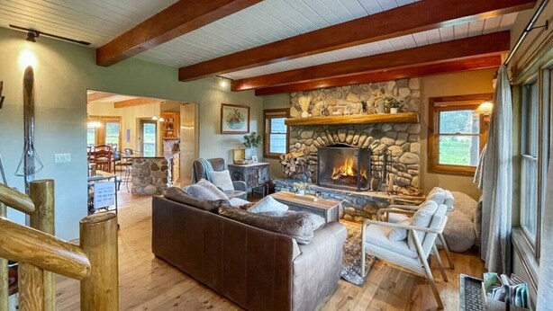 A cozy living room with a stone fireplace, wooden floors, and a modern sofa.