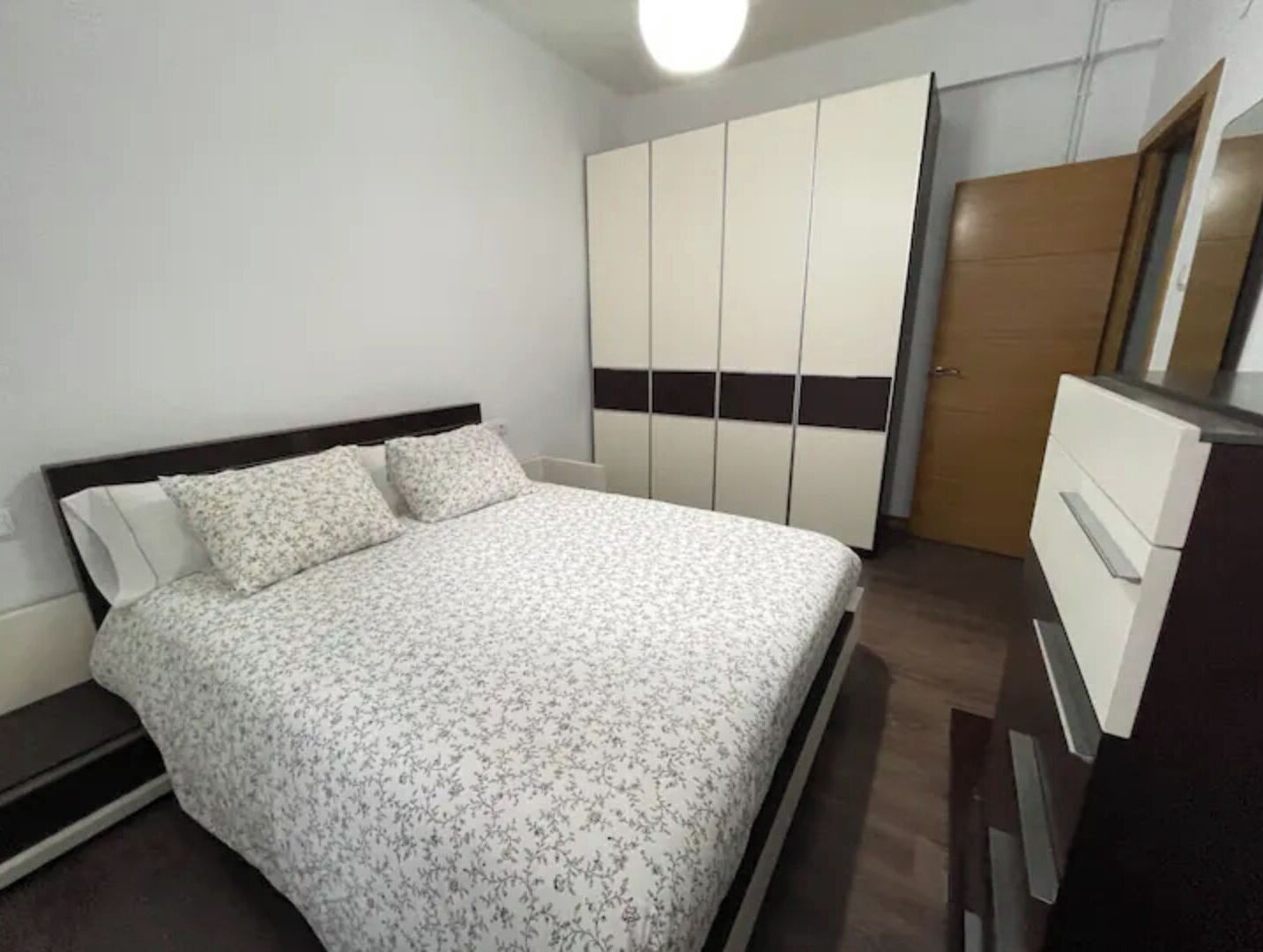 A bedroom with a bed, a wardrobe, and a dresser.