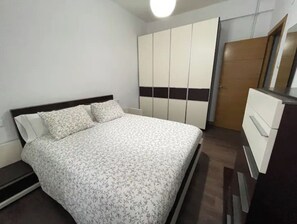 A bedroom with a bed, a wardrobe, and a dresser.