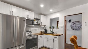 Una cucina moderna con elettrodomestici in acciaio inossidabile, mobili bianchi e un piano di lavoro in legno.