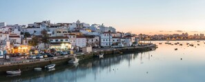 A coastal town with buildings along a waterfront, boats docked, and a calm sea.
