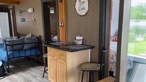 A compact living space with a kitchenette, a dining area, and a sofa. - Cozy Cabin on Cobbossee Lake near Lakeside Marina (Winthrop)