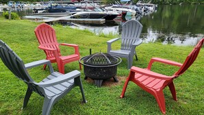 A lakeside seating area with Adirondack chairs and a fire pit. - Cozy Cabin on Cobbossee Lake near Lakeside Marina (Winthrop)