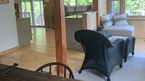 Interior rústico de una cabaña con comedor, cocina y una zona de estar acogedora con vistas al exterior.