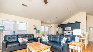 A living room with a sofa set, a coffee table, and a dining area with chairs. - 2 Britt Buoys - Oceanfront 4BR duplex, (Surf City)