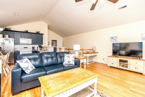 A living room with a leather sofa, wooden coffee table, and a television. - 2 Britt Buoys - Oceanfront 4BR duplex, (Surf City)