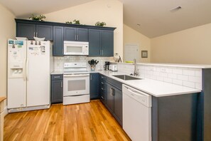 A compact kitchen with dark cabinets, a white microwave, a stove, and a dishwasher.