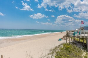 Ein Strand mit einer Holzpromenade, einem Rettungsturm und einer amerikanischen Flagge.