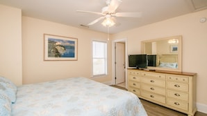 A bedroom with a bed, a dresser, a television, a ceiling fan, and a window with blinds. - 2 Britt Buoys - Oceanfront 4BR duplex, (Surf City)