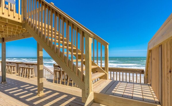 Una escalera de madera que lleva a una terraza frente al mar.