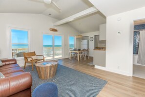 Amplia sala de estar con vista al mar, comedor con mesa y sillas, cocina y un baño independiente.