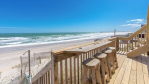 A wooden deck with a railing overlooking a beach and ocean.