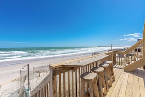 Una terraza de madera con barandilla, con vista a una playa y al océano.