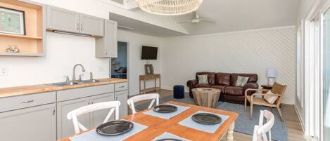 Une cuisine moderne avec des meubles blancs, une table à manger dressée et un ventilateur de plafond.