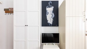 A white wardrobe with a flat-screen TV on a small table beside it.