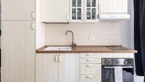A kitchen with white cabinets, a wooden countertop, a sink, a stove, and a window with curtains.