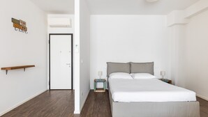 Une chambre à coucher au style minimaliste, avec un grand lit, des tables de chevet, une petite table de nuit et une étagère en bois.