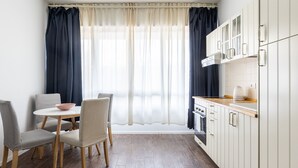 A modern kitchen with white cabinets, a wooden countertop, and a dining area with a round table and chairs. - Largo Molina Studio II by Wonderful Italy (Bologna)
