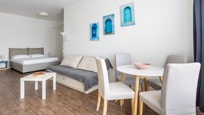 A modern hotel room with a bed, sofa, dining table, and chairs. - Largo Molina Studio II by Wonderful Italy (Bologna)