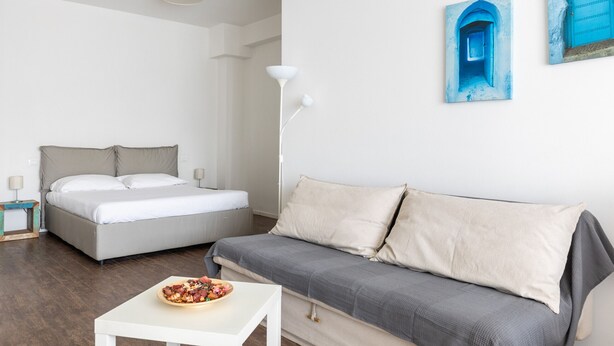 A bedroom with a bed, a sofa, a small table, and a bowl of fruit. - Largo Molina Studio II by Wonderful Italy (Bologna)