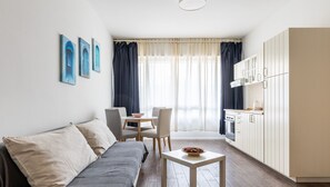 Un salon moderne comprenant un canapé, une table à manger et un coin cuisine.
