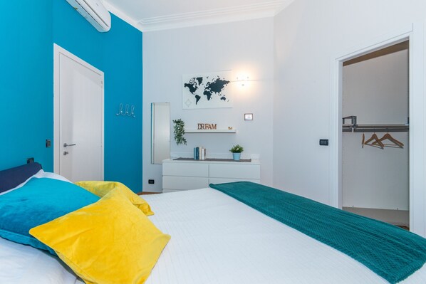 Ein Schlafzimmer mit einem Bett, einer Kommode, einer Weltkarte als Wandbild und einem Schild mit der Aufschrift 'DREAM'.