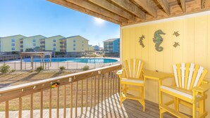 Una terraza de madera con piscina, sillas amarillas y vistas a edificios.