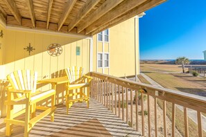 A wooden deck with yellow Adirondack chairs, a star decoration, and a view of the beach.