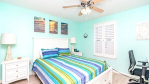 Un dormitorio con cama, mesitas de noche, un escritorio y un ventilador de techo.