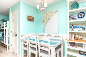 A room with teal walls, a white door, a map on the wall, and a bookshelf with books and decorative items.