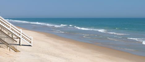 A beach with a staircase leading down to the shore.
