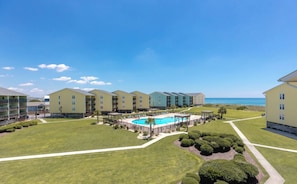 A resort with multiple-story buildings, a central swimming pool, and a view of the ocean. - Sun And Surf - Top Floor 2 BR Surf Condo - Community Pool (Surf City)
