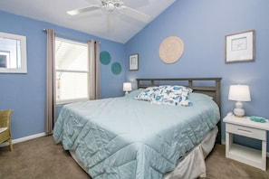 A bedroom with a bed, two bedside tables, a ceiling fan, and a window with curtains. - Sun And Surf - Top Floor 2 BR Surf Condo - Community Pool (Surf City)