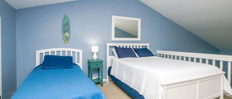 A bedroom with two beds, a ceiling fan, and a small nightstand with a lamp.