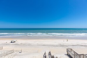 A beach with a wooden walkway leading to the water, a tent, and a sandy area with sparse vegetation. - Borders The Beach - 5BR Oceanfront Home with Amazing Views! (Surf City)