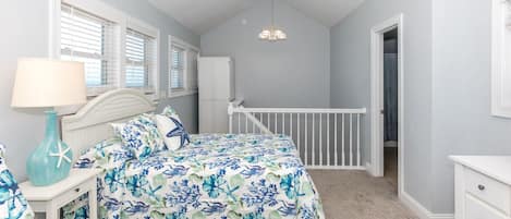 Un dormitorio con cama, mesita de noche, lámpara y vistas al baño.