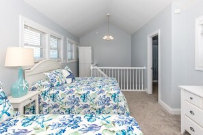 A bedroom with a bed, nightstand, lamp, and a view of the bathroom. - Borders The Beach - 5BR Oceanfront Home with Amazing Views! (Surf City)